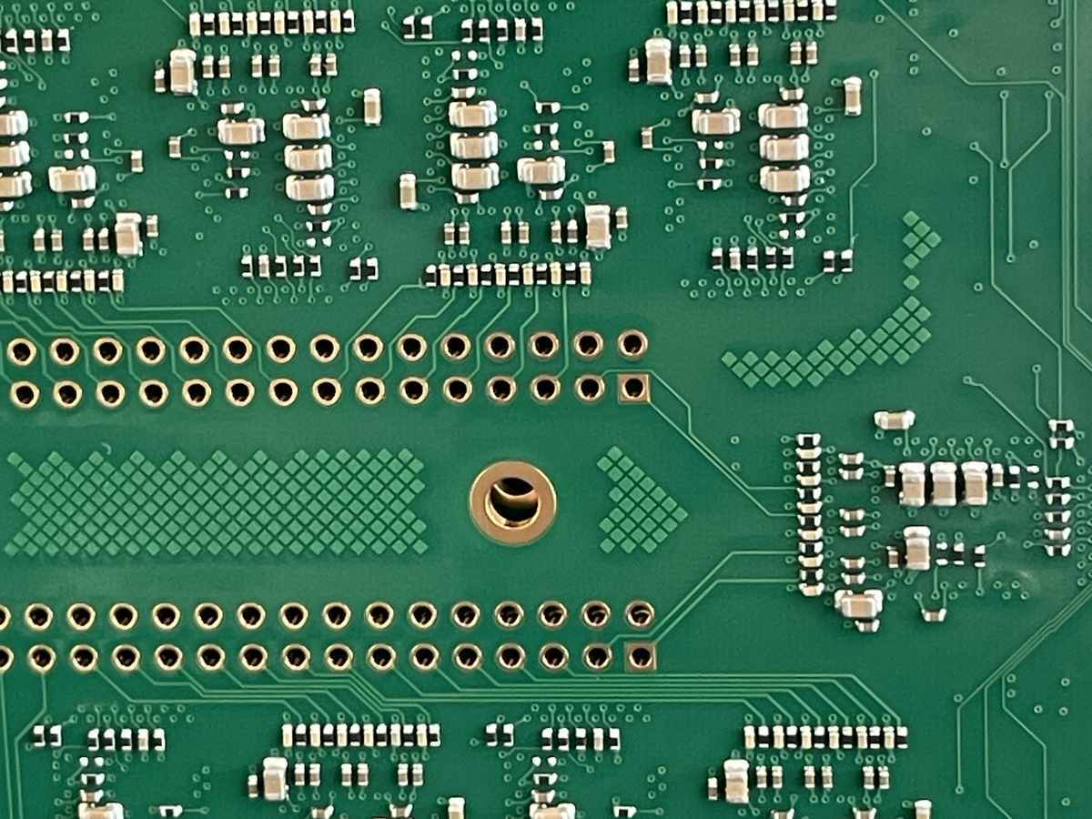 Nahaufnahme einer grünen Leiterplatte mit SMD-Bauteilen und Kontaktpunkten